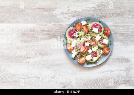 Gesund lecker lecker Salat mit Tomaten, Radieschen, Käse, Sprossen und Sesam in der Platte auf hellen Holz- Tabelle, Ansicht von oben, kopieren. Stockfoto