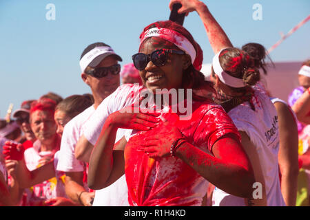 Schwarze afrikanische Dame oder Frau in Rot Farbe pulverbeschichtet mit Sonnenbrille und weißen Stirnband für Foto bei Fun Run Sport Event im Sommer posing abgedeckt Stockfoto