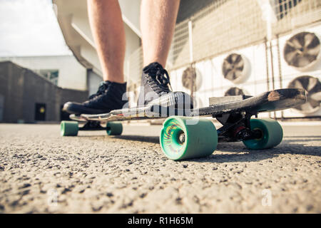 In der Nähe der Beine und Longboard stehen auf Asphalt. Stockfoto