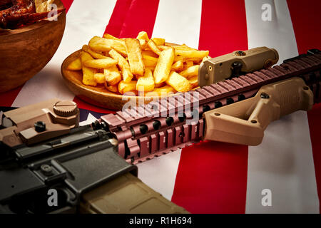 Köstliche Fried Chicken Wings, Pommes frites und Gewehr gegen USA-Flagge im Hintergrund Stockfoto