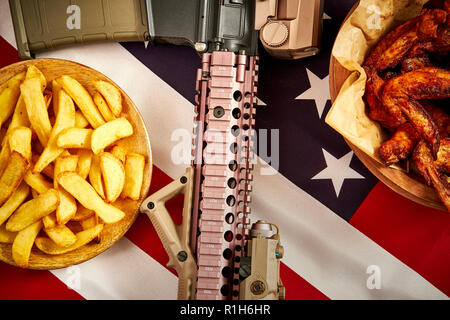 Blick von oben auf die köstliche Fried Chicken Wings, Pommes frites und Gewehr gegen USA-Flagge im Hintergrund Stockfoto