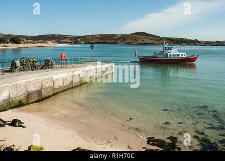 Eine Fähre, die Kirche Quay Jetty, Bryher, an einem schönen sonnigen Tag, blauer Himmel und Meer und goldenem Sand. Isles of Scilly. Stockfoto