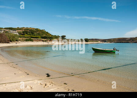 Der wunderschöne Sandstrand von Kirche Quay, bryher an einem sonnigen Tag mit klarer Himmel, blaues Meer und ein kleines blaues Holzboot. Stockfoto