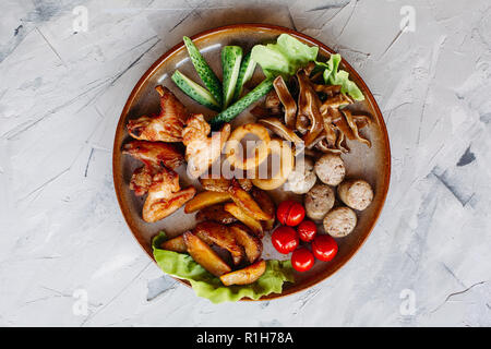 Ton Teller voll von Vorspeisen einschließlich Goldy chrispy Chicken Nuggets mit Kruste, leckere Häppchen mit Hering und Kirschtomaten, serviert mit garl Stockfoto