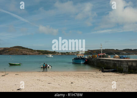 Kirche Quay Jetty mit Anlegestelle der Passagiere, mit Sandstrand, blaues Meer und Himmel und die Inseln von Tresco im Hintergrund. Stockfoto