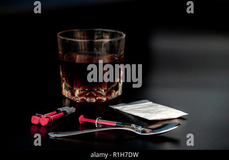 Droge, einem Löffel, Spritzen und ein Glas Whiskey mit schwarzem Hintergrund. Drogen und Alkohol Konzept Stockfoto