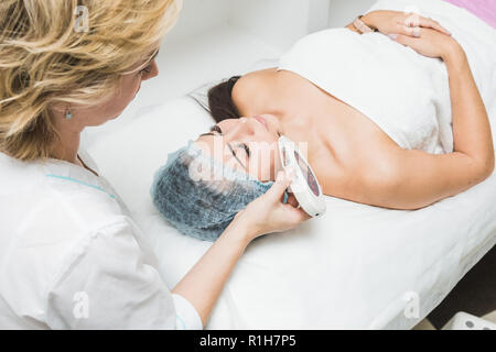 Ein Patient Frau mit geschlossenen Augen liegt in der Arztpraxis. Kosmetische Verfahren in der Kosmetik. Stockfoto