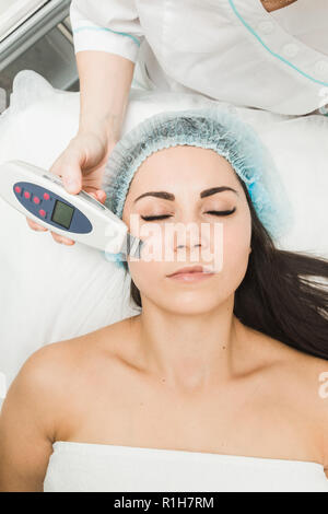 Ein Patient Frau mit geschlossenen Augen liegt in der Arztpraxis. Kosmetische Verfahren in der Kosmetik. Stockfoto