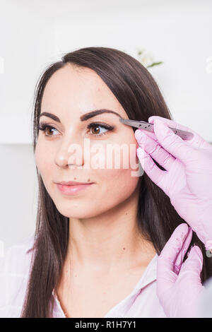 Die Augenbrauen in Form. Kosmetische Verfahren in der Kosmetik. Gesicht des Patienten schließen. Stockfoto