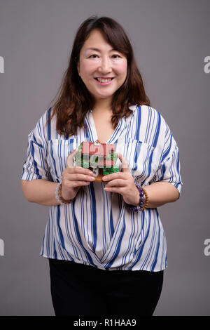 Reifen schöne asiatische Geschäftsfrau holding Haus Figur Stockfoto