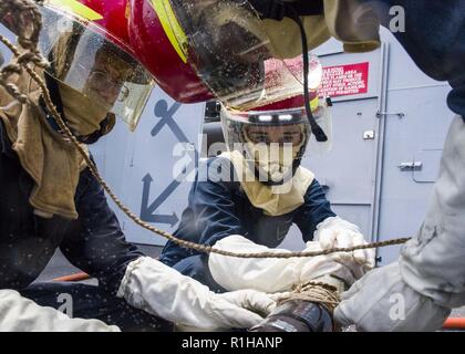 Golf von Aden (Sept. 19, 2018) Matrosen zu San Antonio zugeordnet - Klasse amphibious Transport dock Schiff USS Anchorage LPD (23) ein simuliertes geborstene Leitung während in einem General Quarters Bohrer zu reparieren, während auf einem planmäßigen Einsatz von Essex Amphibious Ready Group (ARG) und dem 13 Marine Expeditionary Unit (MEU). Das Essex ARG/13 MEU ist eine tödliche, flexibel, und anhaltende Navy-Marine Corps Team in die USA 5 Flotte Bereich der Maßnahmen zur Unterstützung der Marine im Einsatz für die Stabilität und Sicherheit in der Region zu gewährleisten und verbindet das Mittelmeer und den Pazifischen durch t Stockfoto