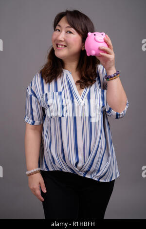 Reifen schöne asiatische Geschäftsfrau Holding piggy Bank Stockfoto