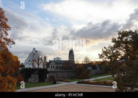 Die Sonne in einem bewölkten Himmel über einem Kirche hinter der alten Stadtmauer in Koblenz, Deutschland. Stockfoto