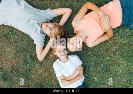 Freundliche Familie von drei Kindern Spaß auf dem grünen Rasen, Ansicht von oben für 3 Kinder. Stockfoto