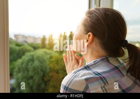 Reife Frau Blick aus dem Fenster Blick auf die Rückseite. Stockfoto