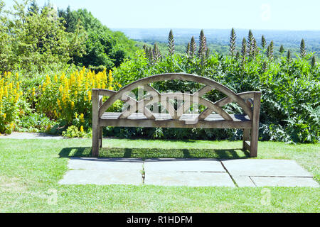 Alte Holzbank auf der Spitze eines Hügels in einem Sommer Garten mit Panoramablick über englische Landschaft. Stockfoto