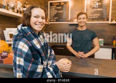 Herbst Winter Porträt der jungen jugendlich Mädchen mit einer Tasse Kaffee und bedeckt mit der Wolldecke plaid Decke im Coffee Shop. Stockfoto