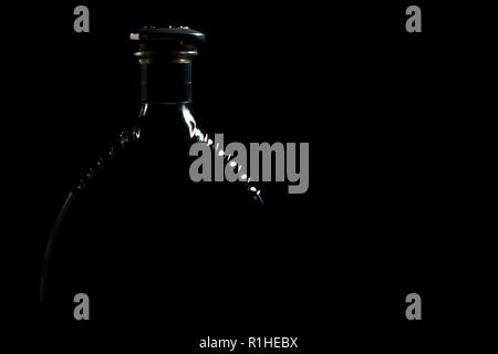 Silhouette von luxuriösen Alkohol Flasche Cognac auf schwarzem Hintergrund Stockfoto