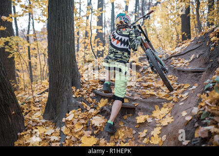 Bild der Athlet im Helm reiten Sport Bike auf dem Weg durch den Wald. Stockfoto