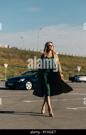 In voller Länge Bild des blonden Jungen auf dem Hintergrund der schwarzen Auto am Nachmittag Stockfoto