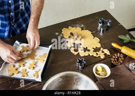 Weihnachten Lebensmittel Konzept. Mann kochen Gingerbread man Cookies in Weihnachten Holztisch in der Küche zu Hause. Weihnachten Dessert Stockfoto