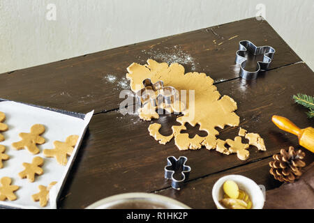 Weihnachten Lebensmittel Konzept. Rohen Teig für Kochen gingerbread man Cookies in Weihnachten auf Holztisch. Weihnachten Dessert Stockfoto