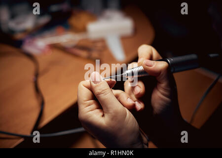 Mädchen griffen Nägel mit einer Fräse für Maniküre. Nahaufnahme Stockfoto