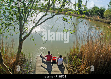 Kinder die kleinen Fischer sitzen auf einem hölzernen Oberfläche und Fischen und Sonnenstrahlen genießen. Stockfoto