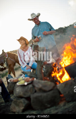 Lächelnd Mann und Frau sitzen am Lagerfeuer. Stockfoto