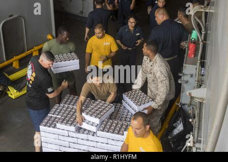 Golf von Aden (Sept. 21, 2018) Matrosen und Marines bewegen liefert, während sie in einer Auffüllung teilnehmenden auf See an Bord Whidbey Island-Klasse dock Landung Schiff USS Rushmore (LSD 47), die während einer planmäßigen Einsatz der Essex Amphibious Ready Group (ARG) und 13th Marine Expeditionary Unit (MEU). Das Essex ARG/13 MEU ist tödlich, flexibel, und anhaltende Navy-Marine Corps Team in die USA 5 Flotte Bereich der Maßnahmen zur Unterstützung der Marine im Einsatz für die Stabilität und Sicherheit in der Region zu gewährleisten, Anschluss an das Mittelmeer und den Pazifischen Raum durch den westlichen In Stockfoto