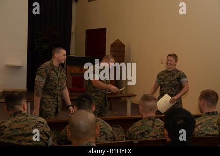 Us Marine Sgt. Ariel Lahtinen, rechts, Lächeln, nachdem Sie ihr Zertifikat von Staff Sgt. Jim Cassidy und Staff Sgt. Justin Territo während der abschlussfeier Für den defensiven Taktiken Tauchlehrer Kurs im Camp Hansen, Okinawa, Japan, Sept. 21, 2018. Während des Kurses können die Teilnehmer mussten 80 Techniken, ihr Zertifikat zu erwerben. Lahtinen, ein Eingeborener von Washingtonville, New York, ist ein platoon Sergeant mit 3. Strafverfolgung Bataillon. Cassidy, ein Eingeborener von Philadelphia und Territo, ein Eingeborener von East Hartford, Connecticut, Kursleiter mit Marine Corps Loslösung, Stockfoto