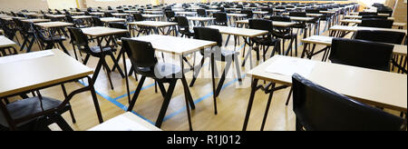 Anzeigen von großen Untersuchungsraum Halle und Prüfung Schreibtische Tische gesäumt in Reihen bereit für Studierende an einer High School zu kommen und ihre Prüfungen Prüfungen Papier sitzen Stockfoto