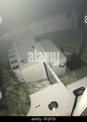 Ein 38-Fuß-Sportboote nimmt auf Wasser in der Biscayne Bay, Florida, Sept. 23, 2018. Ein Coast Guard Station Miami 33-Fuß-Special Purpose Craft-Law Durchsetzung crew angekommen auf Szene, entwässert das Boot mit Hilfe von Miami-Dade Fire Boot 73, legte das Schiff im Schlepptau und übertragen es zum Abendessen Key Marina mit von Verletzungen von den sieben Menschen, die an Bord von Sportbooten. Küstenwache Stockfoto