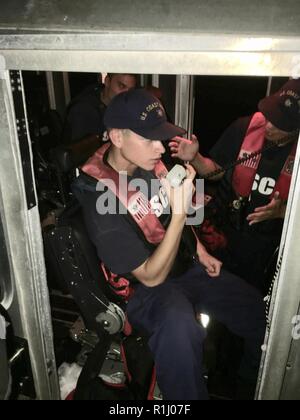 Seaman Wesley Lawson gibt Küstenwache Sektor Miami watchstanders einen situativen Bericht in der Biscayne Bay, Florida, Sept. 23, 2018. Ein Coast Guard Station Miami 33-Fuß-Special Purpose Craft-Law Durchsetzung Crew kam auf die Szene der ein Boot nehmen auf Wasser, entwässert das Boot mit Hilfe von Miami-Dade Fire Boot 73, legte das Schiff im Schlepptau und übertragen es zum Abendessen Key Marina mit von Verletzungen von den sieben Menschen, die an Bord von Sportbooten. Küstenwache Stockfoto