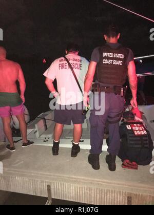 Coast Guard Station Miami 33-Fuß-Special Purpose Craft-Law Durchsetzung Crewmitglieder und Miami-Dade Fire Boot 73 crewmember Entwässern ein 38-Fuß-Sportboote zum Abendessen Key Marina, Florida, Sept. 23, 2018. Ein Coast Guard Station Miami 33-Fuß-Special Purpose Craft-Law Durchsetzung crew angekommen auf Szene, entwässert das Boot mit Hilfe von Miami-Dade Fire Boot 73, legte das Schiff im Schlepptau und übertragen es zum Abendessen Key Marina mit von Verletzungen von den sieben Menschen, die an Bord von Sportbooten. Küstenwache Stockfoto