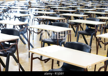 Anzeigen von großen Untersuchungsraum Halle und Prüfung Schreibtische Tische gesäumt in Reihen bereit für Studierende an einer High School zu kommen und ihre Prüfungen Prüfungen Papier sitzen Stockfoto