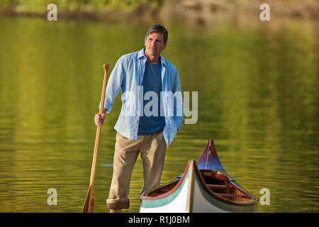 Porträt eines mittleren Alter Mann, der mit seinem Kanu am See. Stockfoto