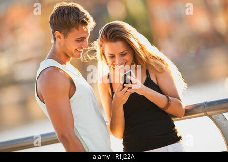 Junges Paar an etwas auf ein Handy suchen. Stockfoto