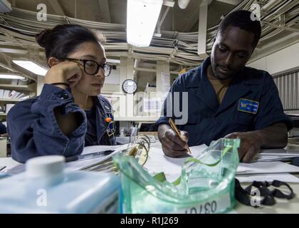 Golf von Aden (Sept. 21, 2018), der Stern Sharon Ferracci, Administration Officer, Links, und Yeoman Seaman Alexander-Gaines, aus Detroit, führen Sie eine Wartung an Bord der San Antonio-Klasse amphibious Transport dock Schiff USS Anchorage LPD (23), die während einer planmäßigen Einsatz von Essex Amphibious Ready Group (ARG) und dem 13 Marine Expeditionary Unit (MEU). Das Essex ARG/13 MEU ist eine tödliche, flexibel, und anhaltende Navy-Marine Corps Team in die USA 5 Flotte Bereich der Maßnahmen zur Unterstützung der Marine im Einsatz für die Stabilität und Sicherheit in der Region zu gewährleisten, conne Stockfoto