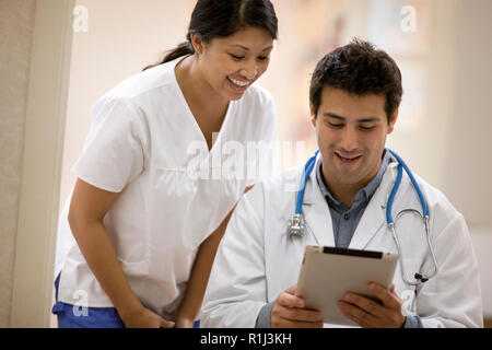 Junge weibliche Krankenschwester diskutieren stellt mit einem Arzt. Stockfoto