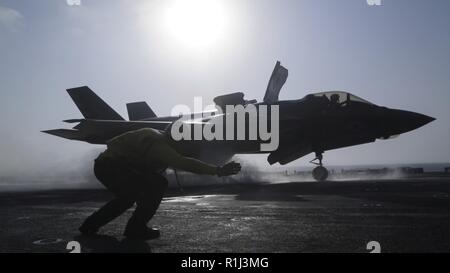 5. US-Flotte BEREICH DER OPERATIONEN - U.S. Navy Petty Officer 1st Class Rey Weiß, einer Luftfahrt boatswains mate Handler mit dem Essex Amphibious Ready Group (ARG), startet eine F-35B Blitz II mit Marine Fighter Attack Squadron 211, 13 Marine Expeditionary Unit (MEU), von der WASP-Klasse amphibisches Schiff USS Essex (LL 2), vor dem ersten Kampf gegen die F-35B, Sept. 27, 2018. Der Essex ist das Flaggschiff der Essex amphibische Gruppe und bereit, mit der begonnen 13. MEU, ist für die US-Fünften Flotte Bereich für Maßnahmen zur Erhöhung der Marineoperationen bereitgestellt maritime Stabilit zu gewährleisten Stockfoto