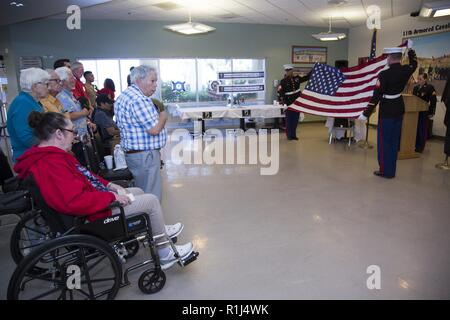 Bewohner von Veteranen nach Hause von California-Barstow, stehen für den Treueeid als sergeants Edward Rojas und Kenneth Mullins, entfalten und halten Sie die amerikanische Flagge als Cpl. Alicia K. Frost steht an Aufmerksamkeit hinter dem Podium. Stockfoto