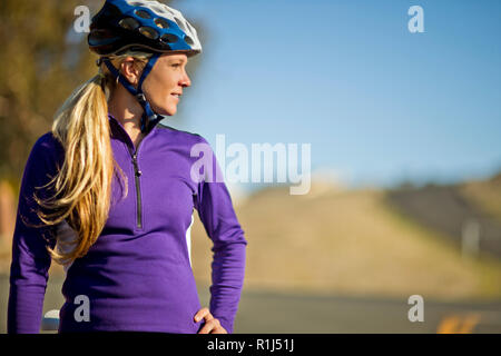 Junge Frau nimmt einen Bruch von unten Radfahren eine Landstraße, um die Ansicht zu bewundern. Stockfoto