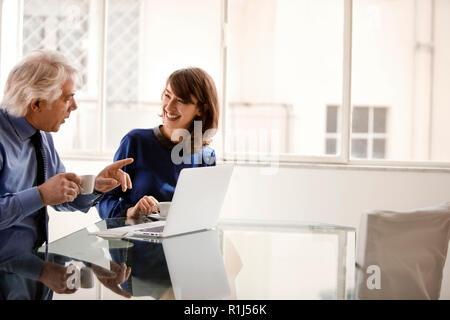 Lächelnd Kollegen diskutieren über ein Laptop. Stockfoto