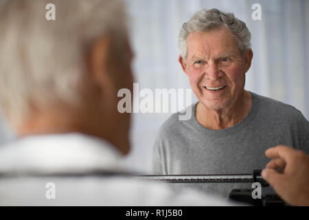 Lächelnd reifer Mann paßt seinen Arzt einrichten Waagen vor einer ärztlichen Untersuchung. Stockfoto