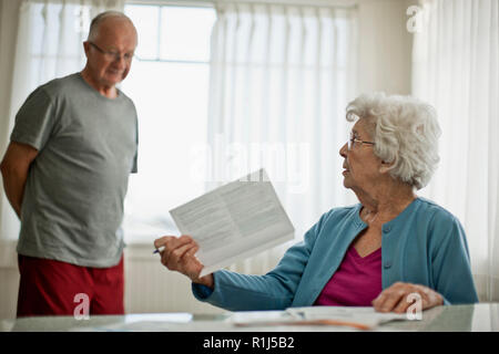 Ältere Frau bittet ihren Mann besorgt über eine Rechnung, die Sie erhalten haben. Stockfoto