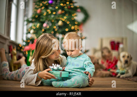 Junge Mädchen ihre Schwester ein Weihnachtsgeschenk geben. Stockfoto