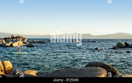 Aktive junge Frau paddleboarding über einen See. Stockfoto