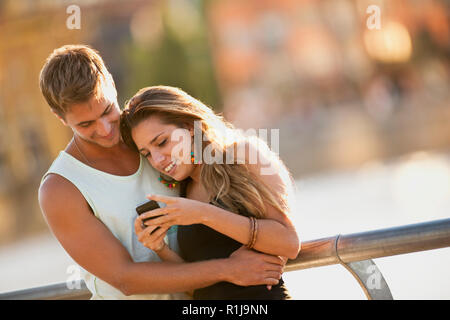 Junges Paar an etwas auf ein Handy suchen. Stockfoto