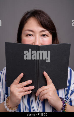 Portrait von Reifen schöne asiatische Geschäftsfrau lesen Buch Stockfoto